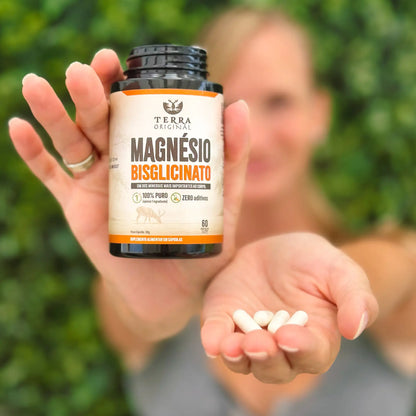Pessoa apresentando frasco de magnésio bisglicinato Terra Original com cápsulas brancas na palma da mão